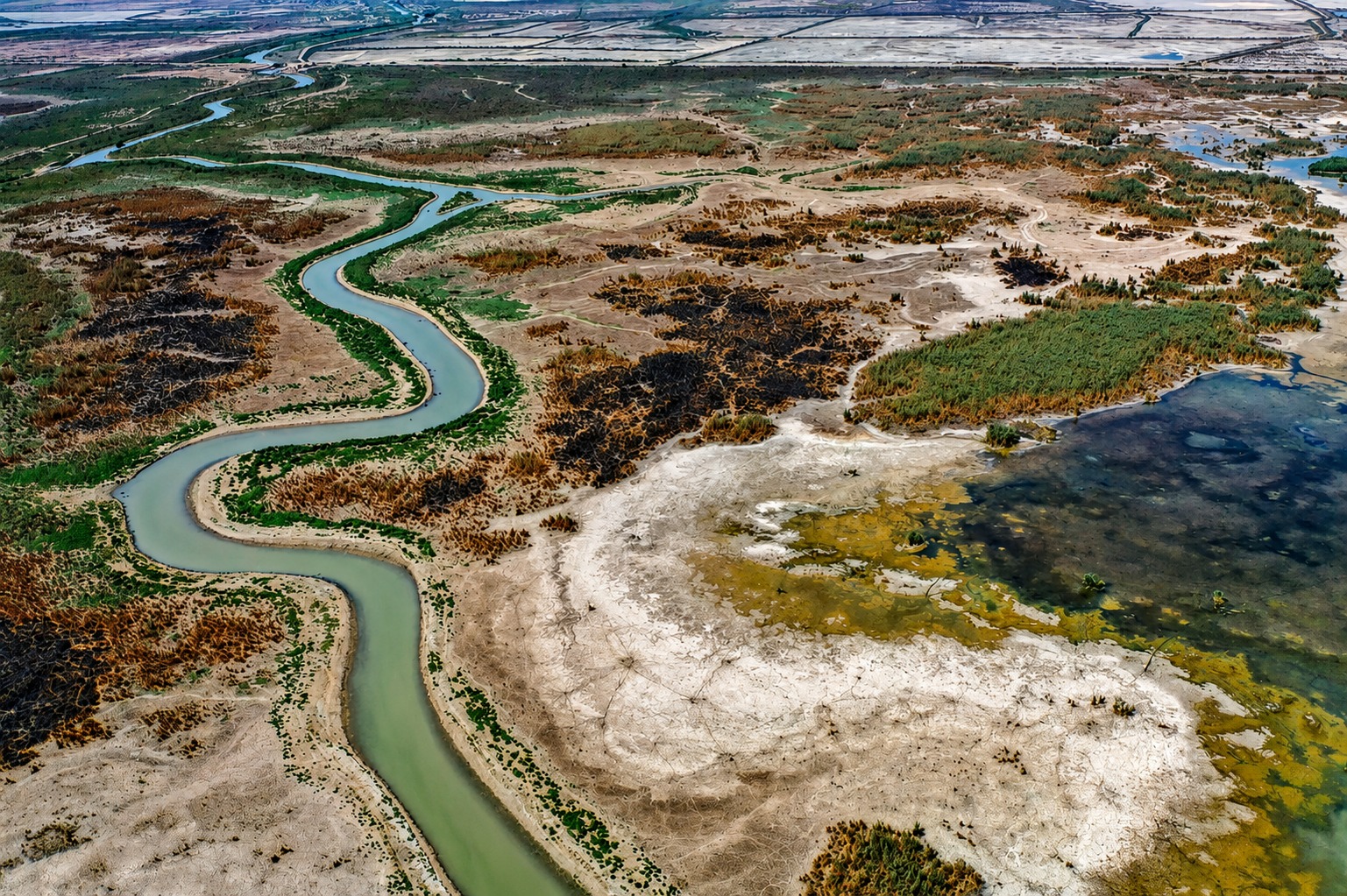 Aerial view of a winding river through the Iraqi marshlands and plains.
